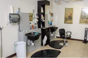 Small salon area with two styling stations and sinks, swivel chairs, mirrors, and framed wall art.