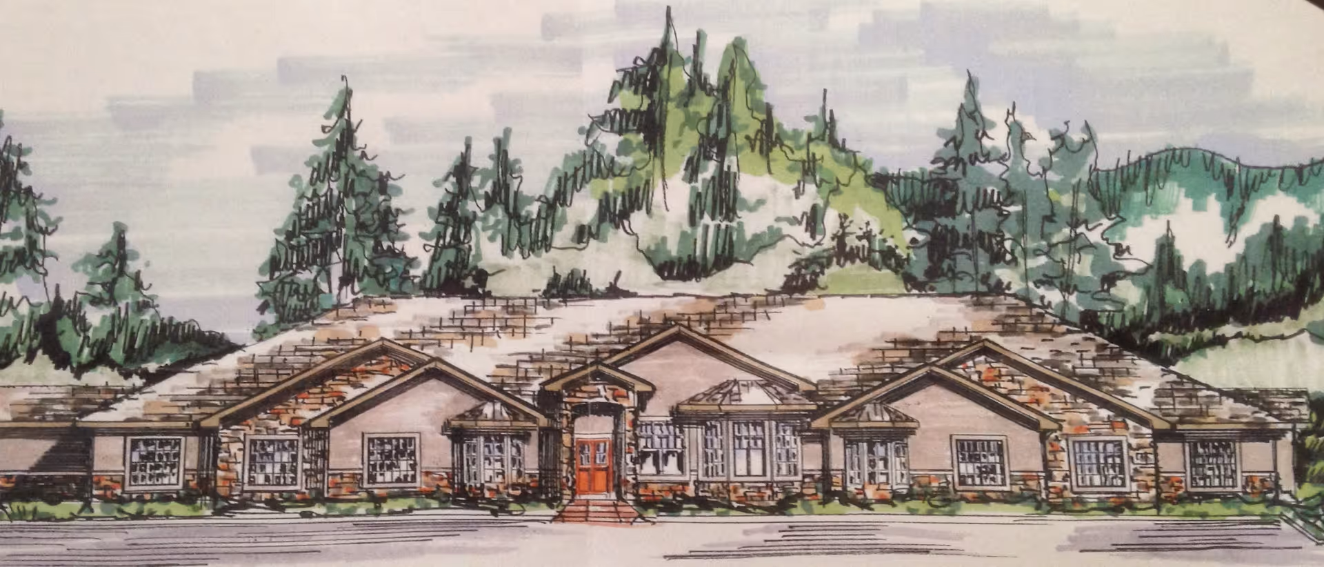Hand-drawn front view of a single-story building with gabled roofs, stone accents, and trees and mountains behind it.