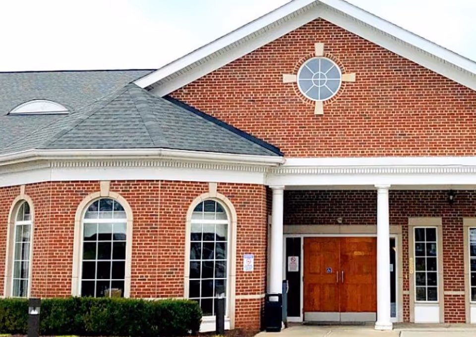 Red brick senior living facility front facade with arched windows and columns.