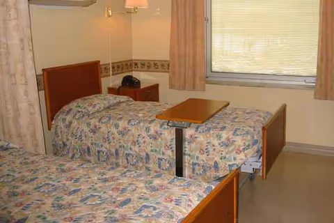 Two single beds with floral bedspreads in a shared hospital-style bedroom
