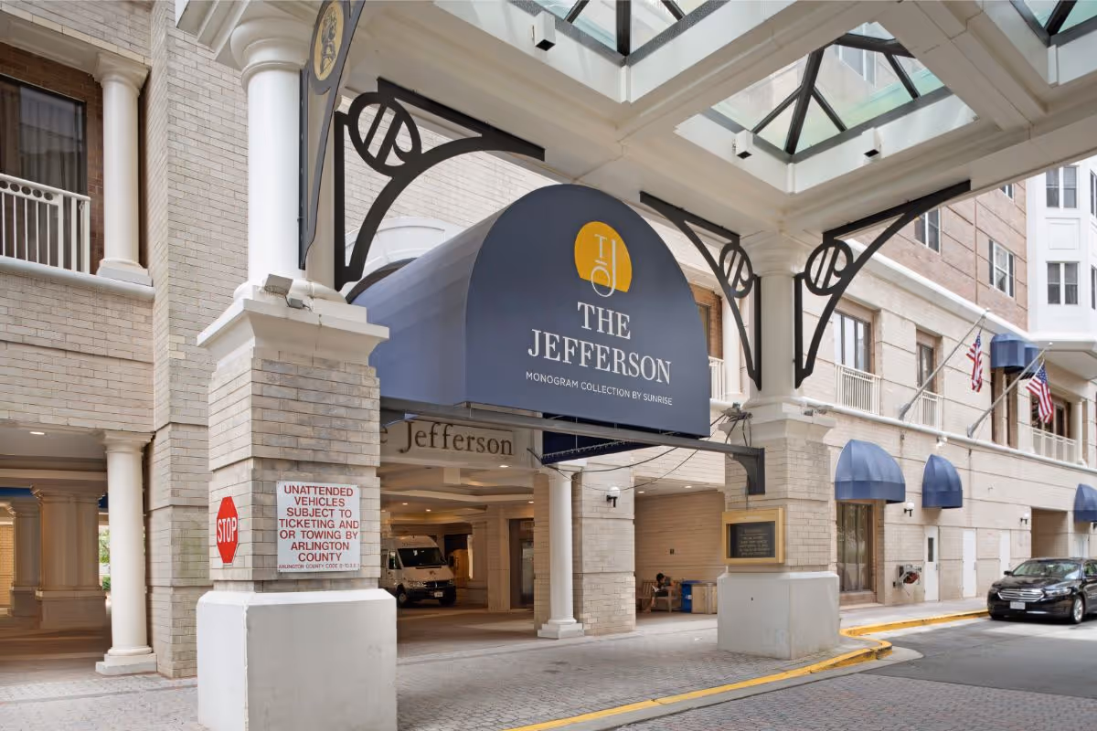 Entrance canopy and porte-cochere of The Jefferson building with a blue awning displaying the name and a covered driveway.