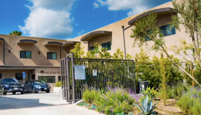 Melrose Villas exterior: gated entrance, landscaped front, and several parked cars along the driveway.