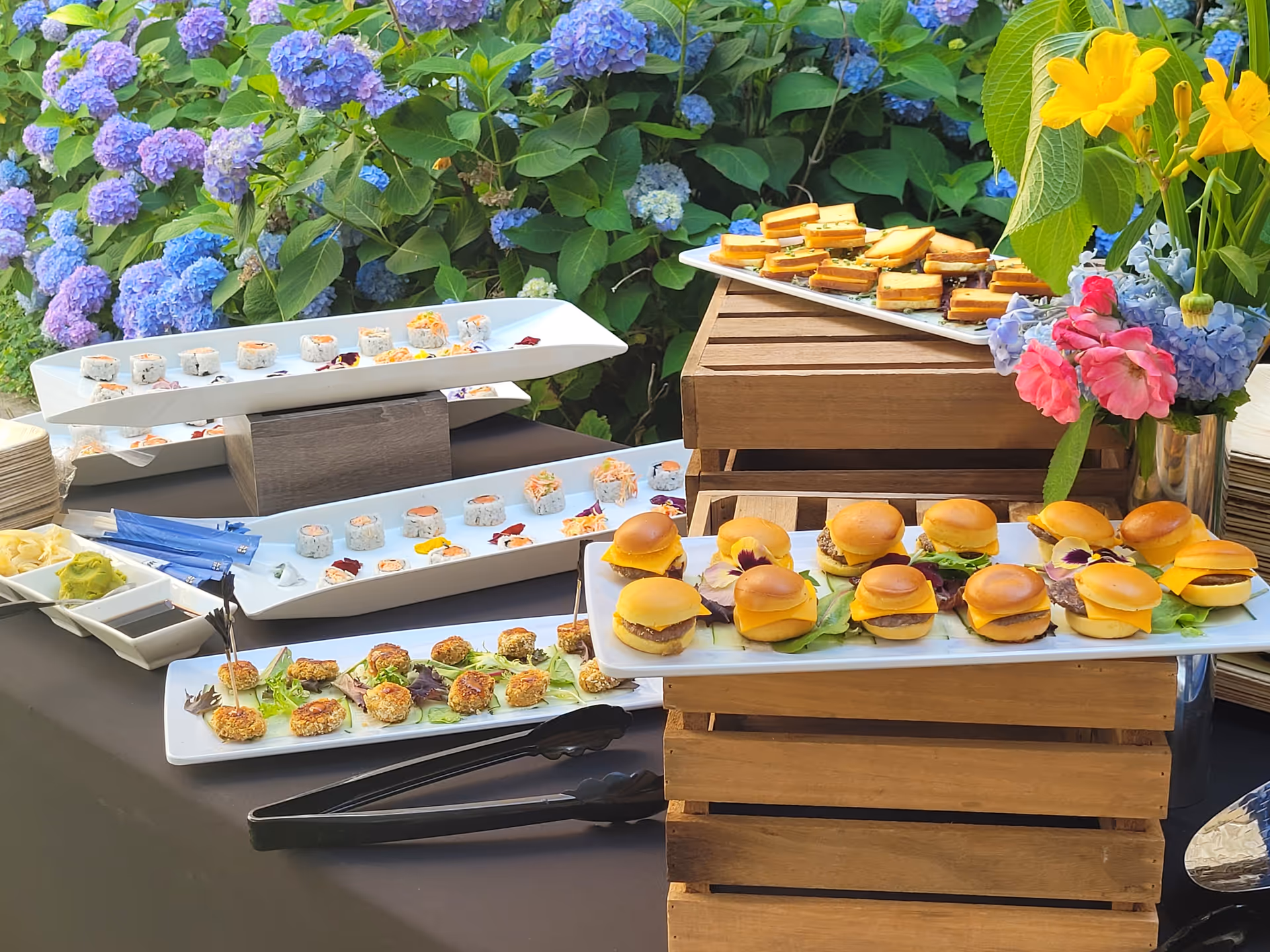 An assortment of gourmet appetizers displayed on trays with a floral background.