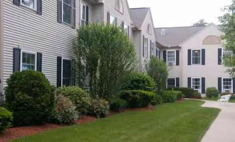 Exterior view of Benchmark Senior Living at Nashua Crossings with manicured lawn and shrubs.