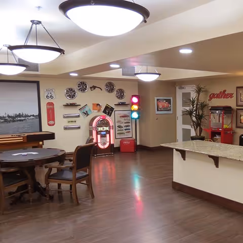 Communal activity room with tables and chairs, a jukebox, decorative traffic light, popcorn machine and a countertop.