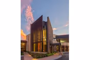 Exterior view of Westminster Village building with brick and glass facade at dusk.