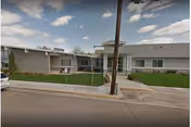 Front exterior of Pioneer Place Assisted Living with lawn, sidewalk, and street