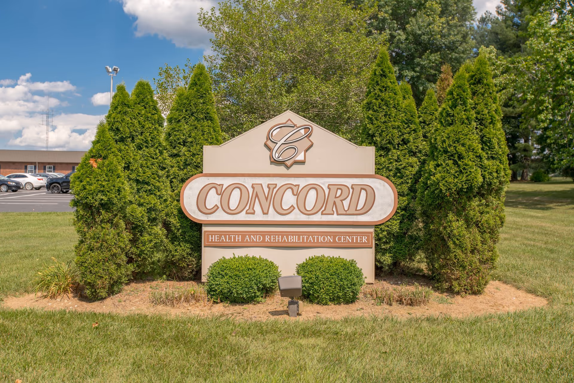 Entrance sign reading "Concord Health and Rehabilitation Center" surrounded by shrubs on a grassy lawn.