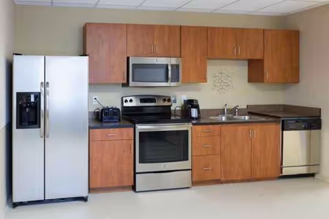 A modern kitchen in a senior living facility with stainless steel appliances and wooden cabinets.