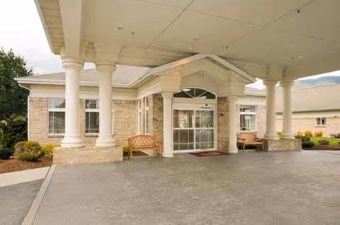 Front entrance of Life Care Center of Sandpoint with a covered porte-cochere and benches.
