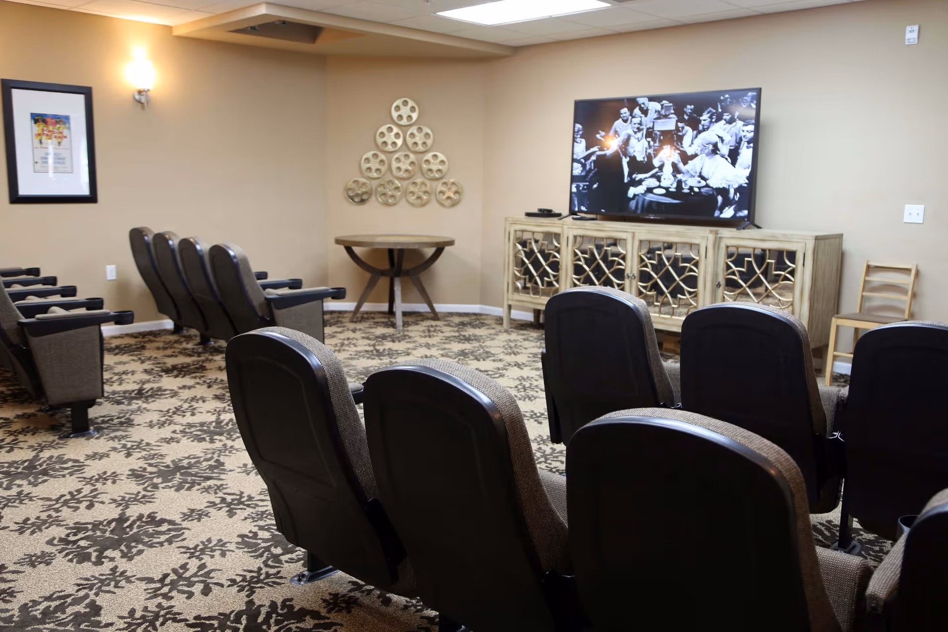 Small screening room with rows of theater seats facing a large TV on a decorative console.
