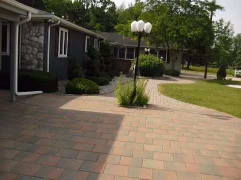 Exterior view of a senior living facility with a brick-paved walkway and green landscaping.