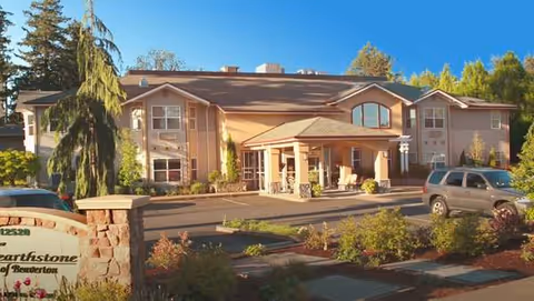 Exterior view of Hearthstone at Murrayhill senior living facility with entrance and landscaping.