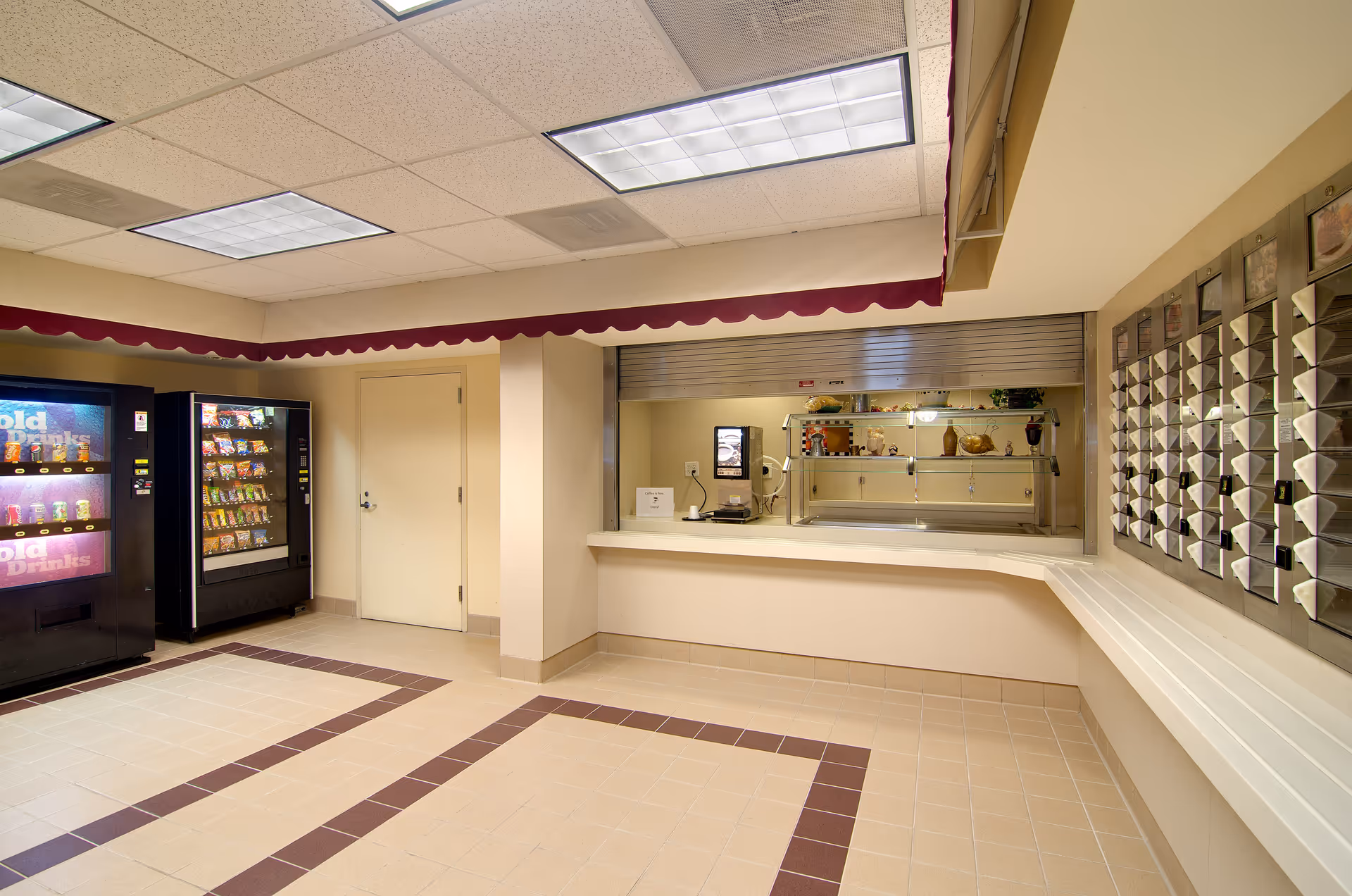 Interior common area with vending machines, a service counter with a pass-through window, and a wall of mail slots.