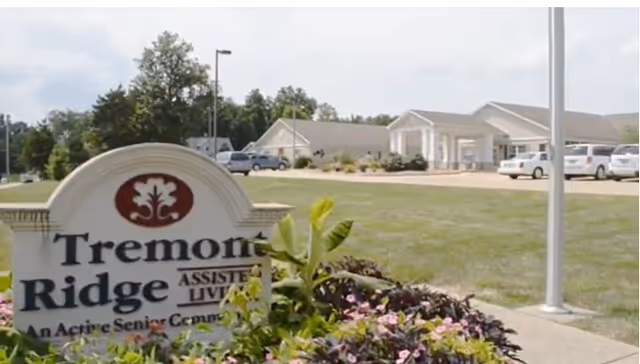Entrance sign for Tremont Ridge Assisted Living with the facility building and parked cars in the background.