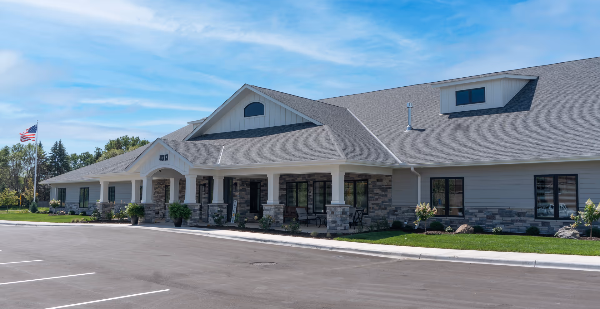 Exterior view of Northwoods Memory Care Suites building with entrance, parking, and landscaping.