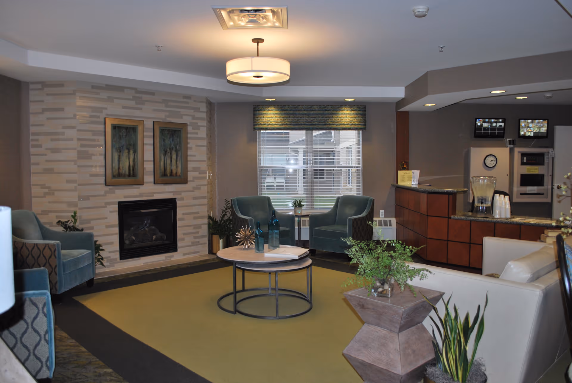 Lobby-style lounge with armchairs around a coffee table, a fireplace, and a reception counter.