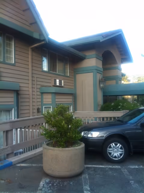 Exterior view of Magnolia Garden Assisted Living showing the building, parking, and a large planter.