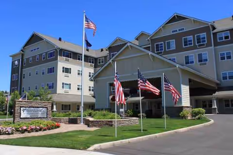 Exterior view of Garden Way Retirement Community building with flags and manicured lawn.