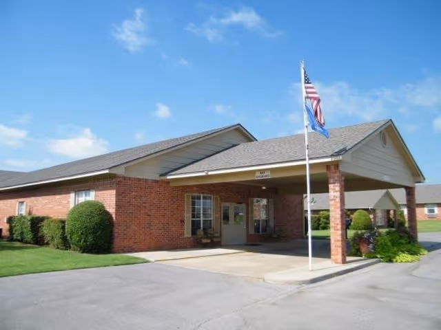 Brick senior living facility with a covered entrance and flagpole at the front.