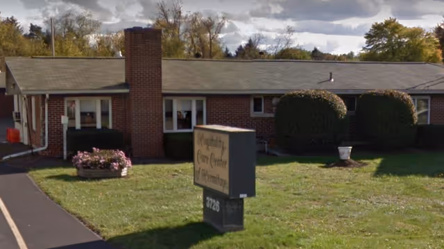 Single-story brick care center building with trimmed bushes and a freestanding sign on the front lawn.