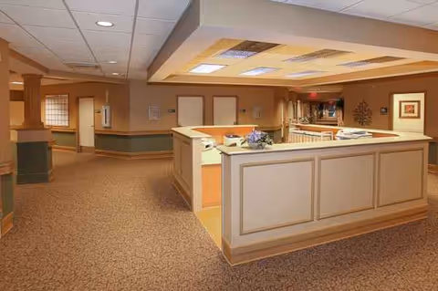 Reception desk in a warmly lit Life Care Center lobby with carpeted hallways.