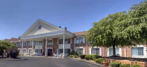 Exterior view of Brookdale Novi building with brick facade, columns, entrance, and trees.