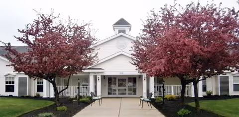 Front entrance of Glenwell senior living community with red trees and seating.