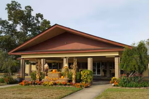 Front view of a nursing and rehabilitation center with pumpkins and landscaping.