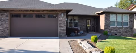 Front view of a brick senior living facility with a garage and landscaped yard.
