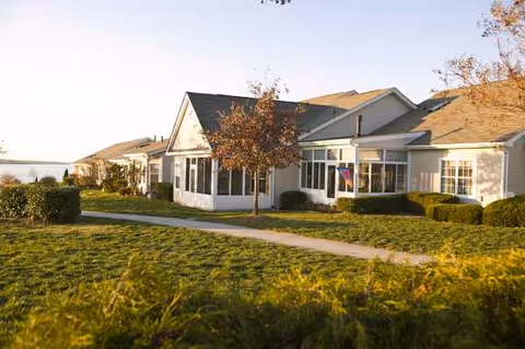 Exterior view of a senior living facility with a manicured lawn and walkway.