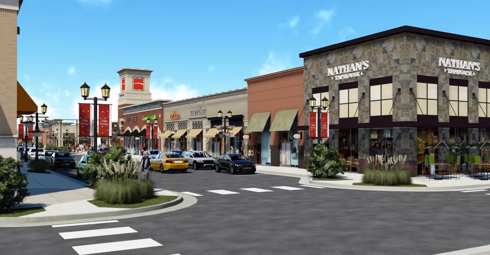 A street view of a shopping district with multiple storefronts including Nathan's Fish House. Several cars are parked along the street and a few people are walking on the sidewalks. The sky is clear and blue, and there are decorative street lamps and banners lining the sidewalks.