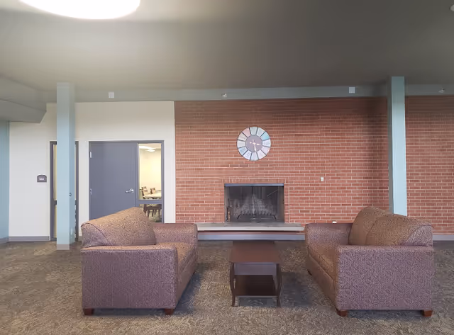 A lounge area with two upholstered sofas facing a coffee table and a brick fireplace on the far wall.