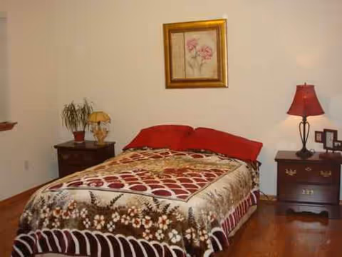 Cozy bedroom with floral quilt, two nightstands, lamps, and wall art.