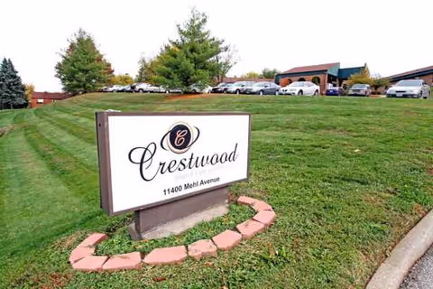 Crestwood Health Care Center sign on a grassy lawn with the building and parking lot behind.