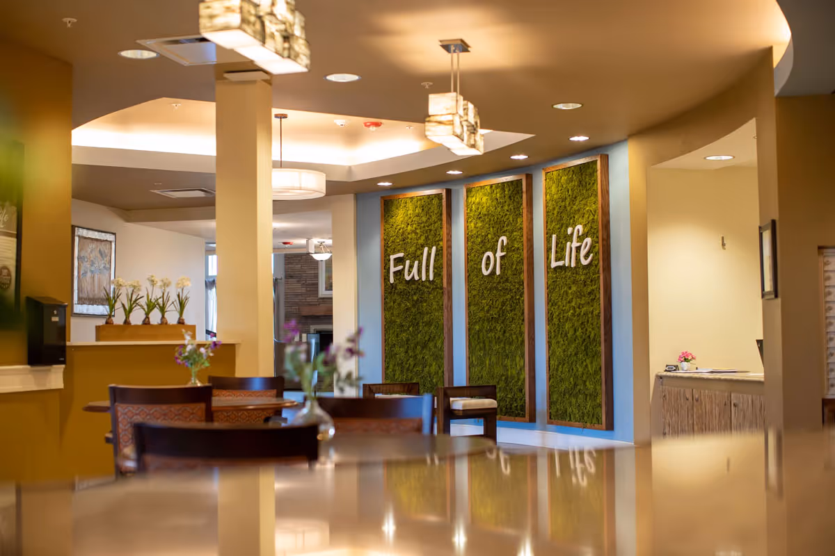 Dining area with tables and chairs facing three tall green wall panels that read "Full of Life".