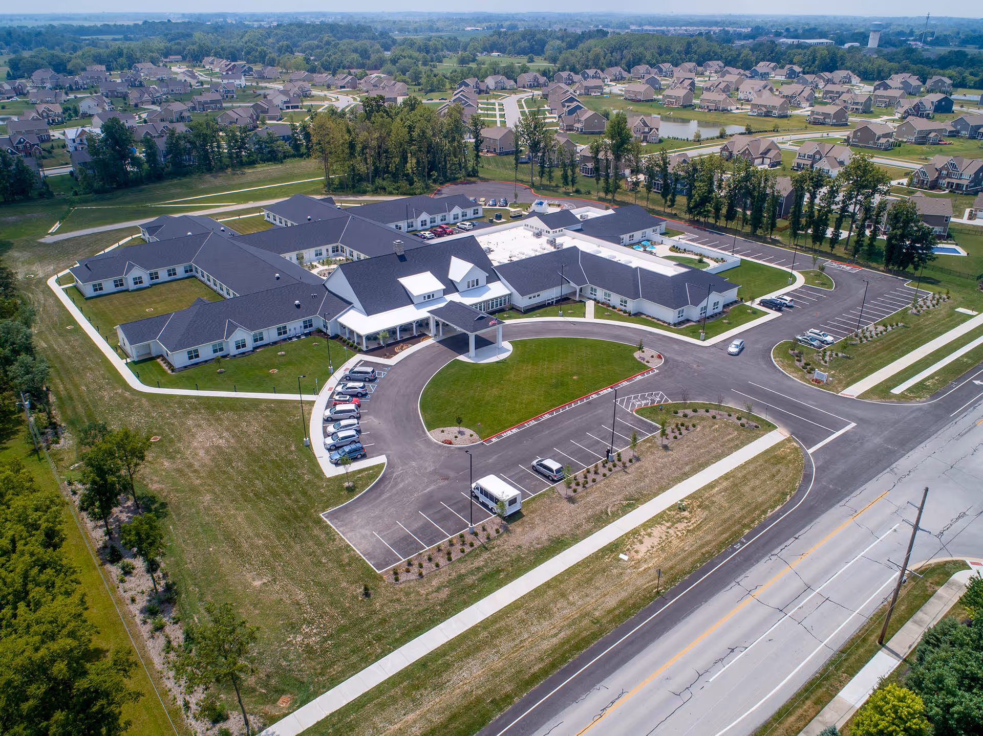 Aerial view of Demaree Crossing senior living facility with a circular driveway, parking lots, and surrounding neighborhood.