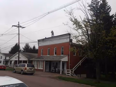 Red brick two-story Johnson's Personal Care Homes building on a street; a person stands on roof.