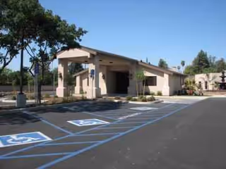 Front exterior of Twin Oaks Rehabilitation and Nursing Center with a covered entry and parking.