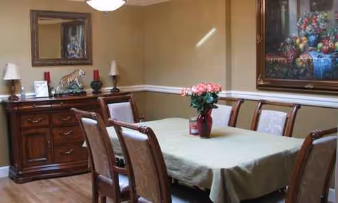 Dining room with a table, chairs, and a vase of flowers.
