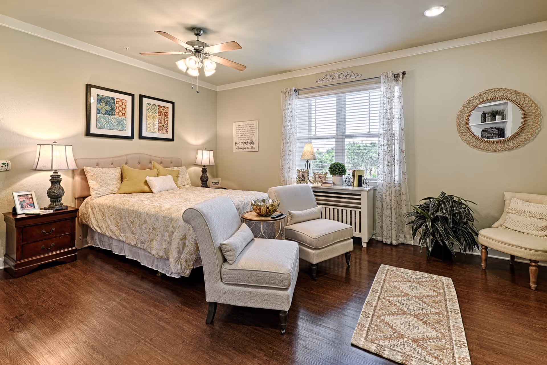Sunny, well-decorated bedroom with a bed, two armchairs, bedside tables, and a window with curtains.