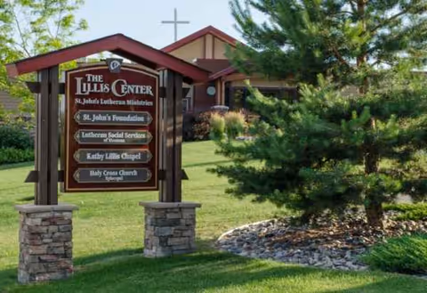 Exterior view of St. John's United facility with sign and landscaped entrance.