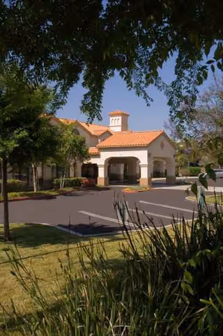 Exterior view of Aegis Living Ventura with a stucco building and orange-tiled roof.