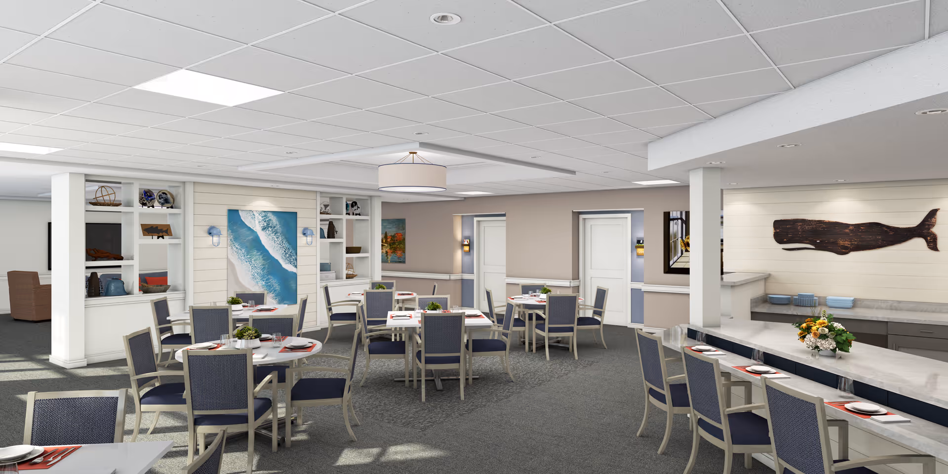 Bright communal dining room with multiple tables set for meals, blue-upholstered chairs, built-in shelving and coastal artwork on the walls.
