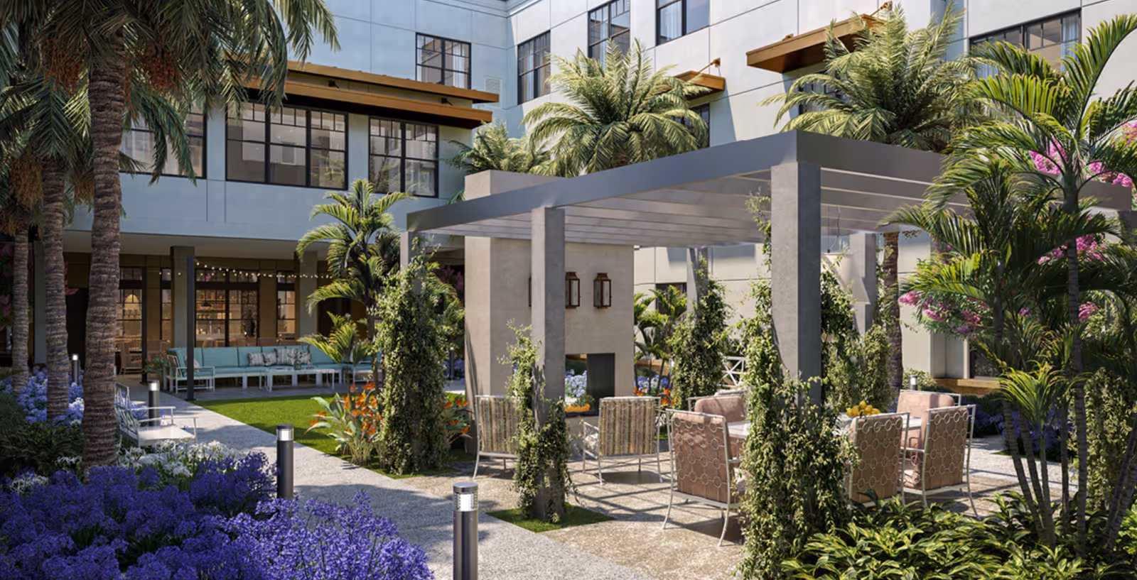 Courtyard with a pergola-covered seating area, patio chairs and tables, and lush tropical landscaping in front of a multi-story building.