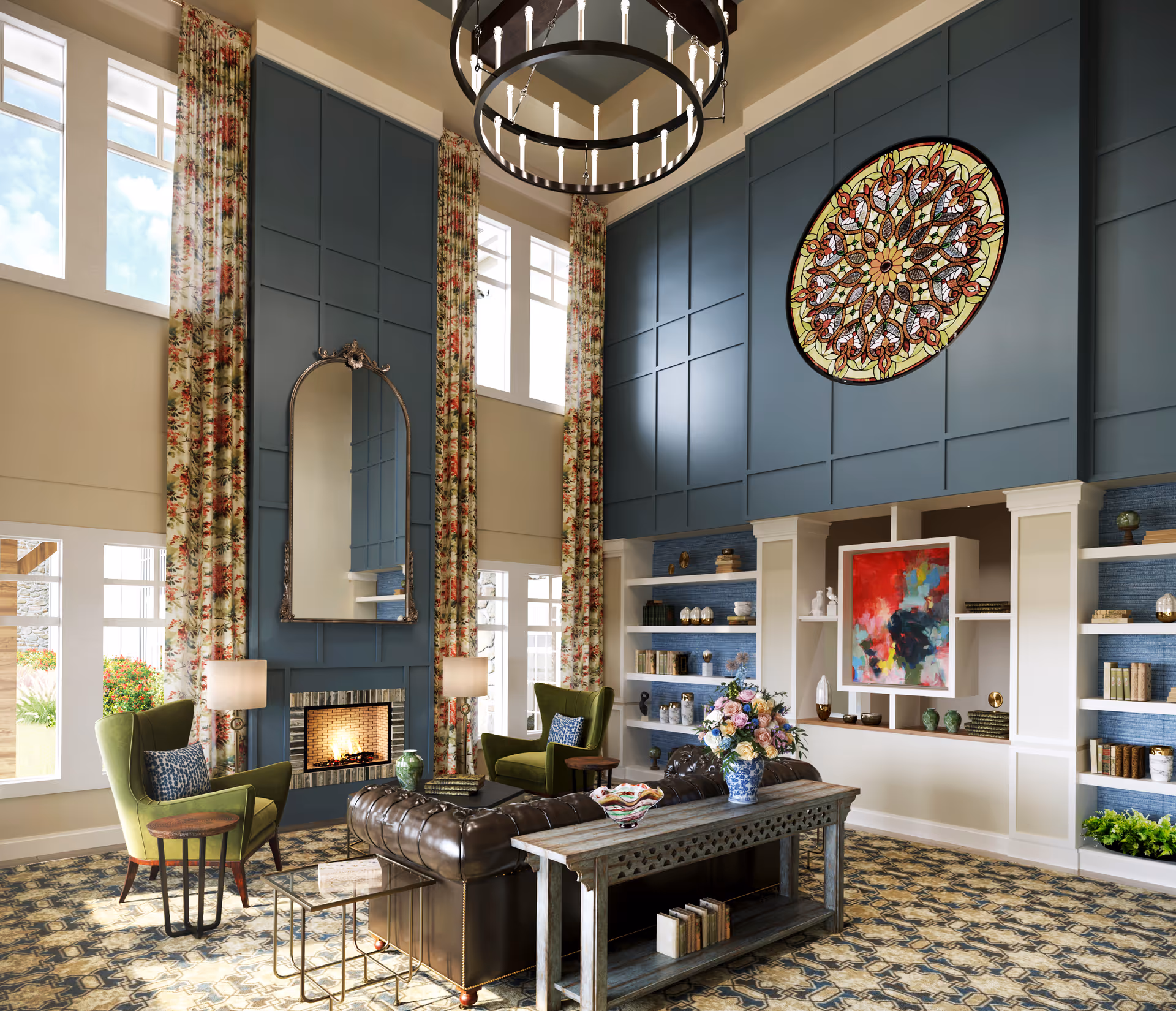 A spacious and elegant living room with high ceilings, large windows with floral curtains, a fireplace with a tall mirror above it, two green armchairs, a dark leather sofa, a wooden console table with a flower vase, built-in white shelves with books and decorative items, a colorful abstract painting, and a large circular stained glass window on a blue paneled wall.