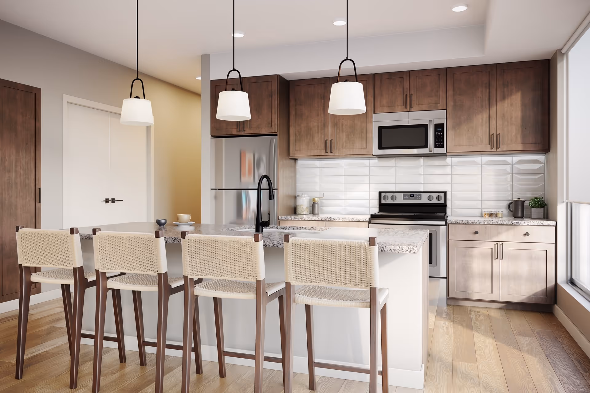 Modern kitchen with wooden cabinets, a stainless steel refrigerator, stove, and microwave. There is a kitchen island with a granite countertop and four woven bar stools. Three pendant lights hang above the island, and there is a large window letting in natural light.