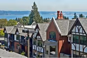 Row of Tudor-style senior housing with a waterfront view and trees in the distance.