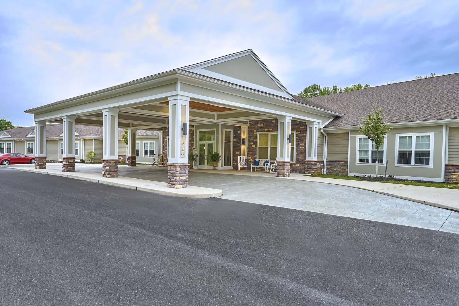 Front exterior of Harmony Village CareOne at Cherry Hill featuring a covered entrance with white columns and a paved driveway.