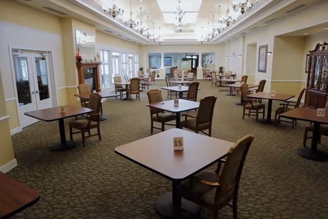 Spacious dining room with multiple numbered square tables and chairs arranged under chandeliers.